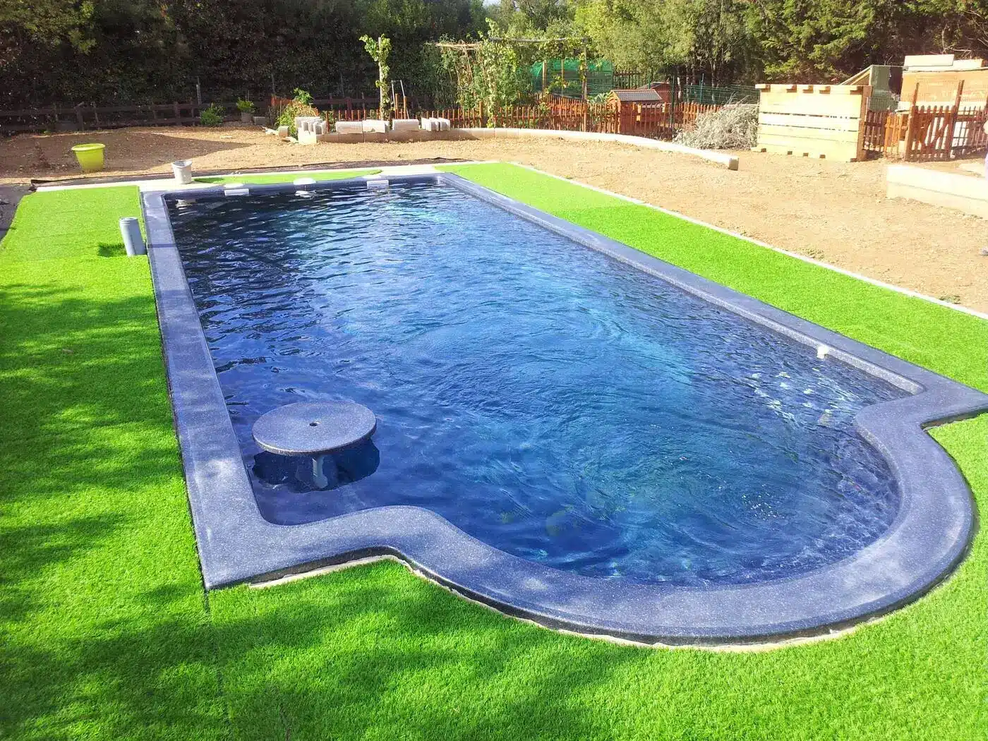 Piscine coque Freedom Majestic, forme libre à extrémité arrondie, dans un jardin engazonné
