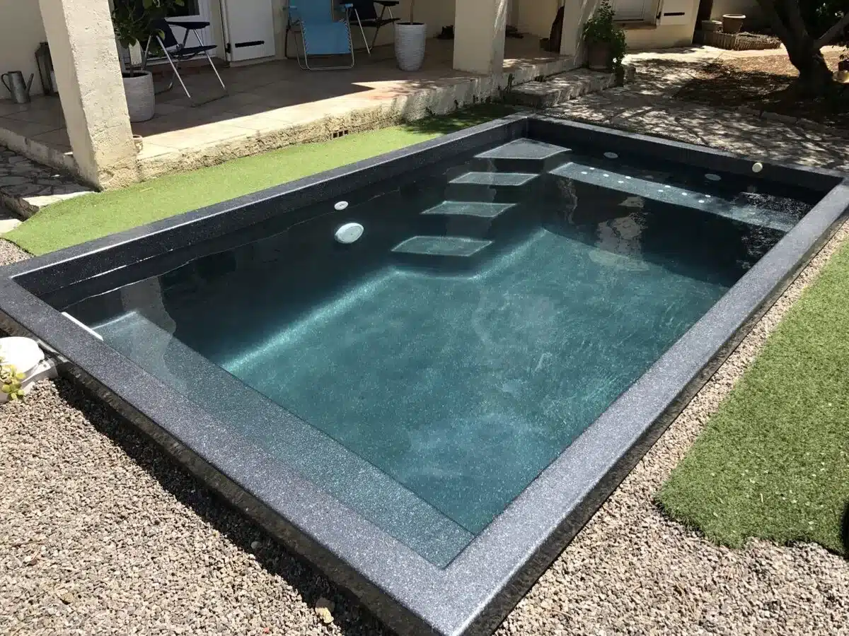 Petite piscine coque Freedom avec escalier intégré, installée dans une cour