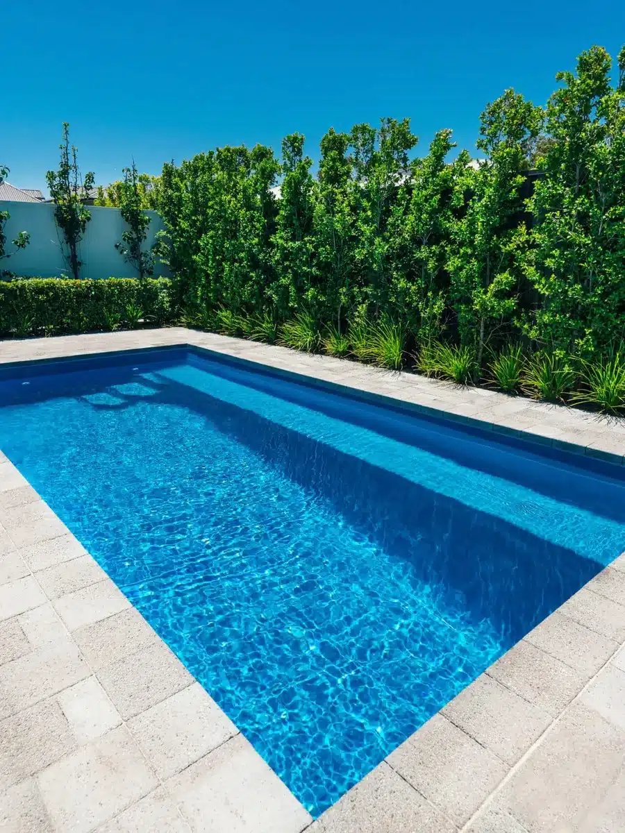 Mini piscine coque Sidney bordée de dalles claires et d'une haie