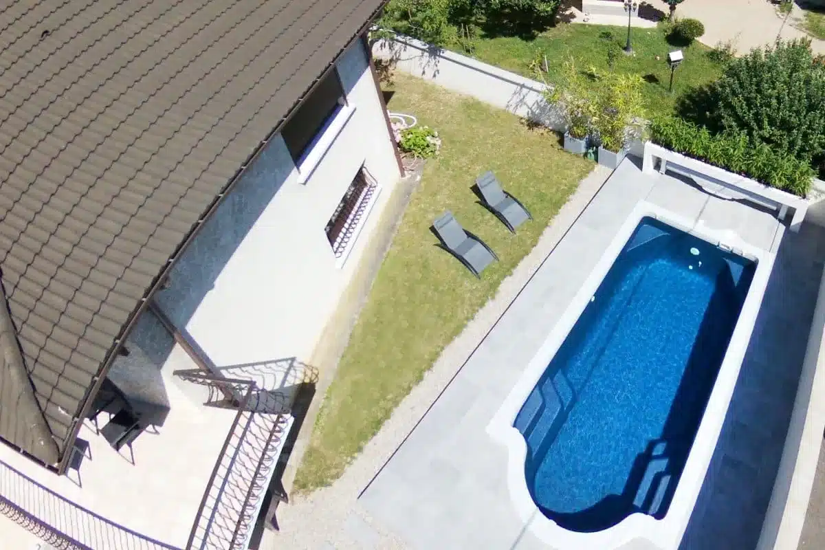 Vue aérienne d'une piscine coque Lagoona implantée le long d'une maison