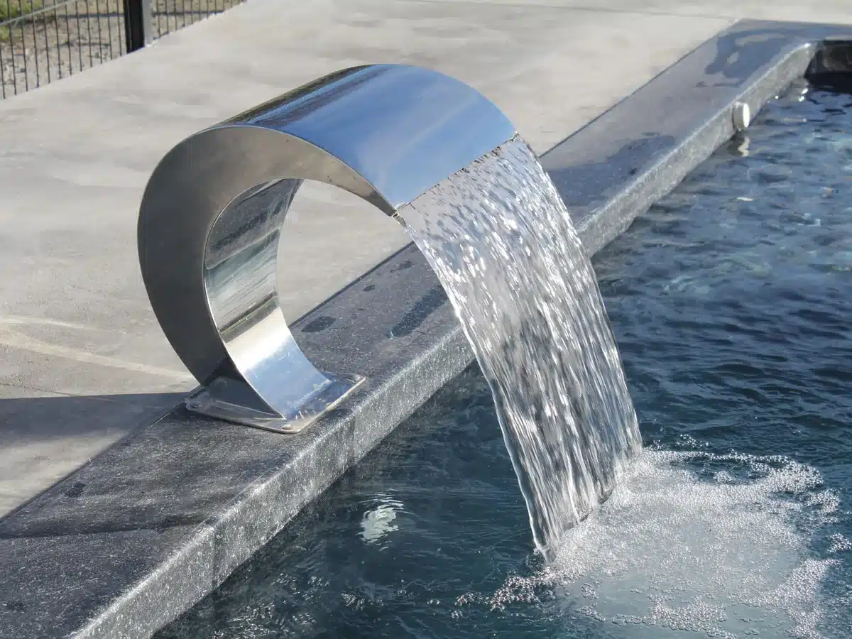 Cascade inox déversant une lame d'eau dans un bassin