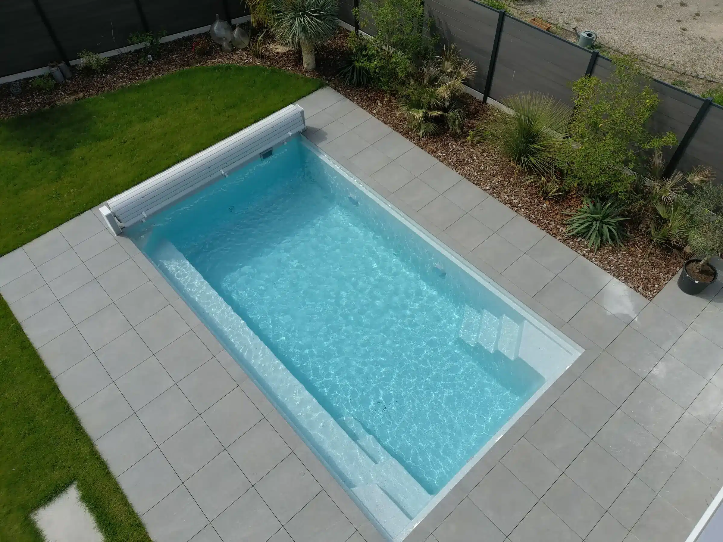 Piscine coque Freedom Atlantis 7 vue du ciel, entourée d'une terrasse en dalles grises